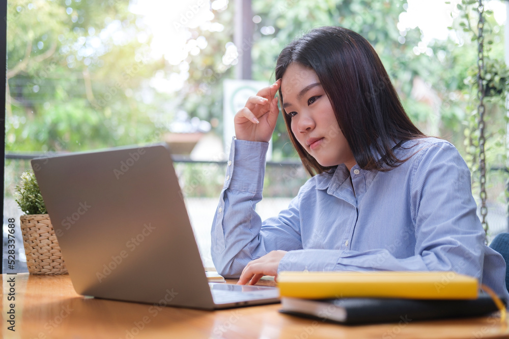 Serious young woman office worker looking at laptop screen and thinking solving online problem. Serious young woman office worker looking at laptop screen and thinking solving online problem.
