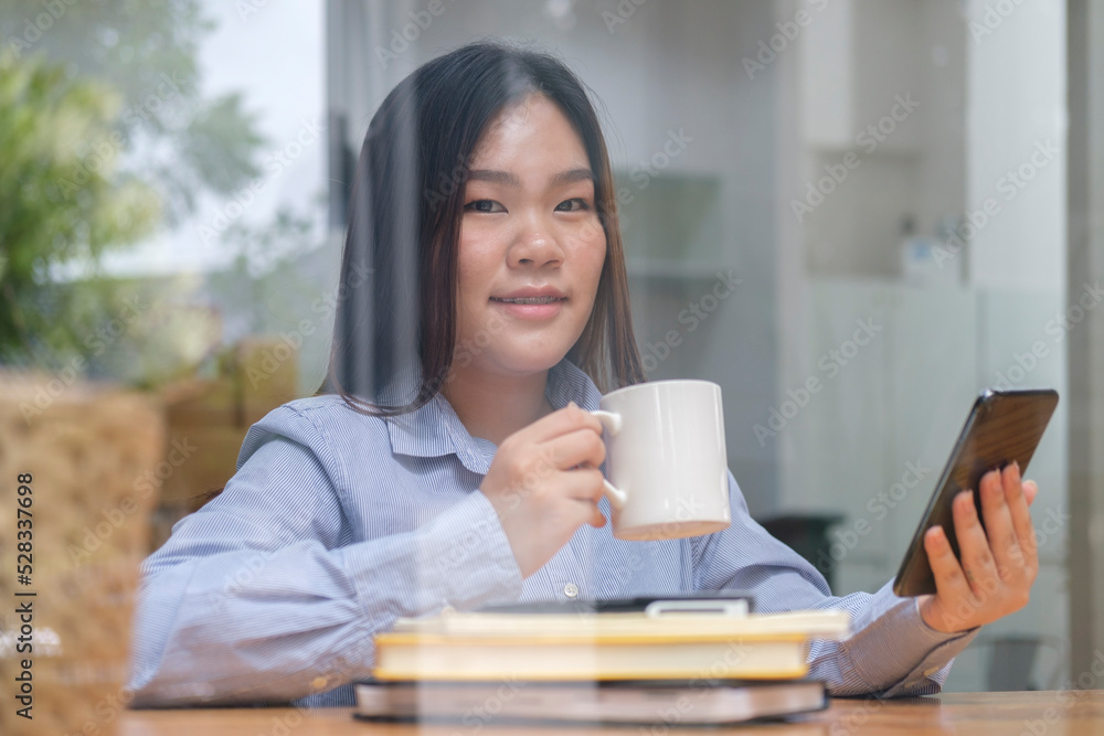 Smiling asian woman sitting in modern coffee shop and using mobile phone. Smiling asian woman sitting in modern coffee shop and using mobile phone.