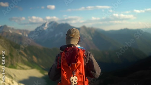 Rack focus from mountain landscape to caucasian man walking out to hiking viewpoint
