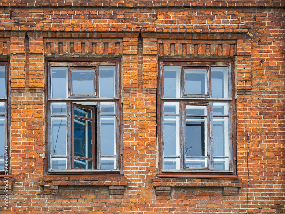 Two windows of the old mansion 19 century with brown bricks wall