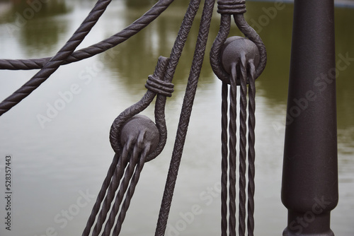 Fencing element on the lake in the form of the rigging of an old ship photo