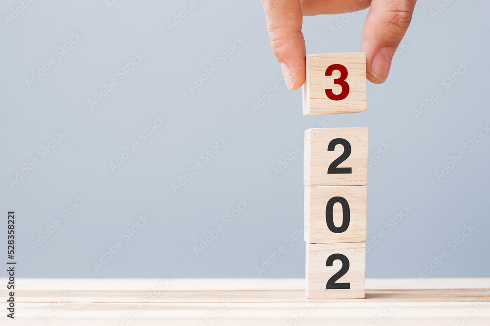 hand holding wooden cube block with 2023 text on table background. Resolution, plan, review, goal, start and New Year holiday concepts hand holding wooden cube block with 2023 text on table background. Resolution, plan, review, goal, start and New Year holiday concepts