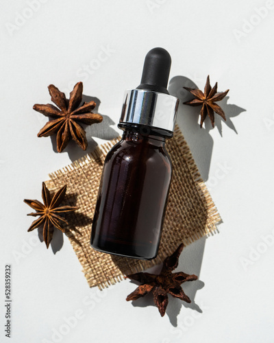 Star anise essential oil in a bottle on a white table. Alternative medicine. A small bottle with star anise essential oil. Anise essential oil, selective orientation. ethereal. Selective focus. 