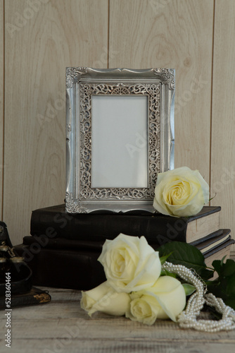 Photo frame, book and flowers on table