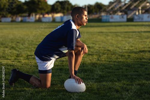Side view of rugby player kneeling with a ball photo