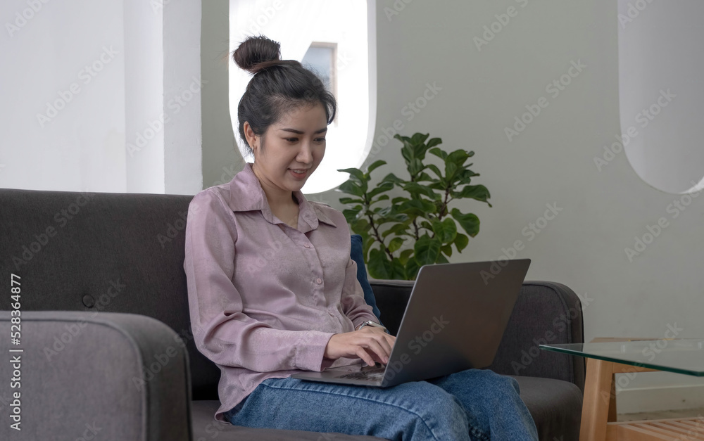 Young business freelance Asian woman working on laptop checking social media while lying on the sofa when relax in living room at home. Lifestyle latin and hispanic ethnicity women at house concept. Young business freelance Asian woman working on laptop checking social media while lying on the sofa when relax in living room at home. Lifestyle latin and hispanic ethnicity women at house concept.