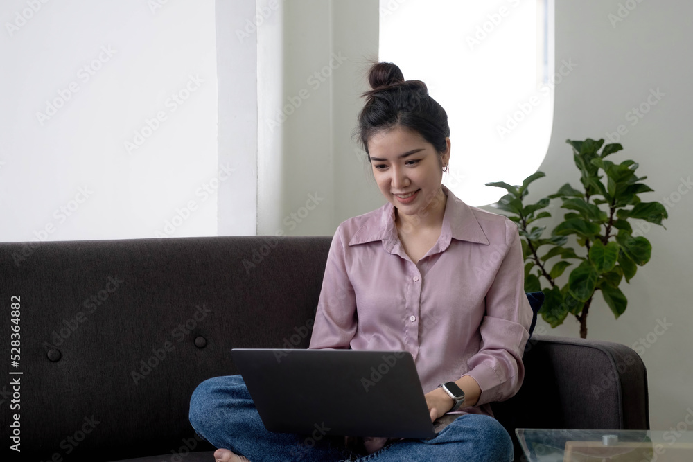 Young business freelance Asian woman working on laptop checking social media while lying on the sofa when relax in living room at home. Lifestyle latin and hispanic ethnicity women at house concept. Young business freelance Asian woman working on laptop checking social media while lying on the sofa when relax in living room at home. Lifestyle latin and hispanic ethnicity women at house concept.