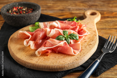 Board with slices of delicious jamon on wooden table, closeup