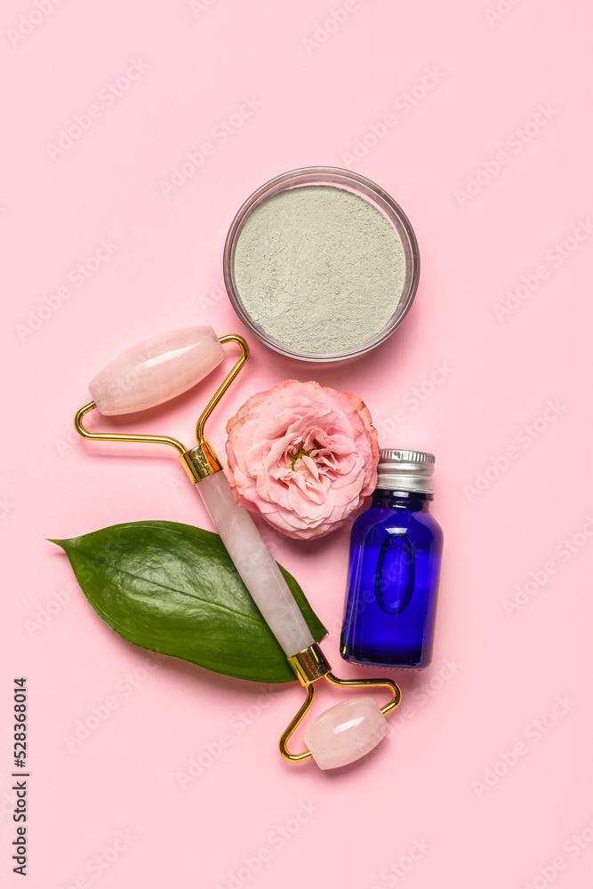 Facial massage tool with cosmetic products and flower on pink background Facial massage tool with cosmetic products and flower on pink background