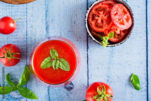 Fresh tomato juice with basil leaves in a glass. Homemade organic drinks. Top view. Closeup