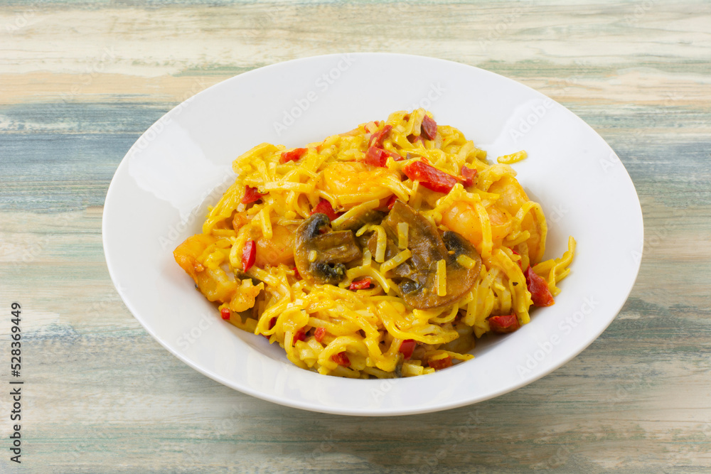 Curry shrimp pasta with mushrooms and red bell peppers dinner in white dinner bowl