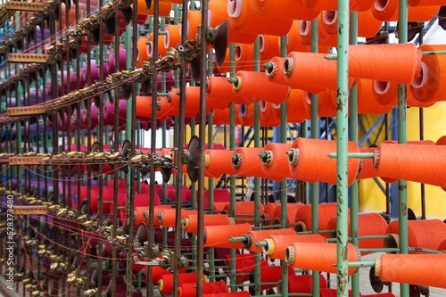 Spools with colored linen warp threads on a weaving machine.