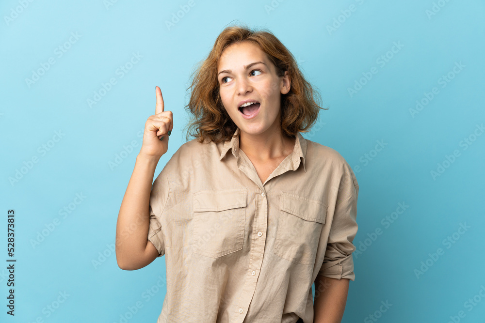 Young Georgian woman isolated on blue background intending to realizes the solution while lifting a finger up Young Georgian woman isolated on blue background intending to realizes the solution while lifting a finger up