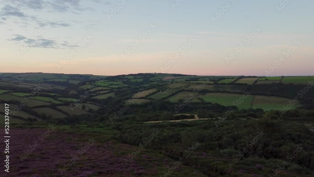 4K Aerial Drone Sunrise Pushing Shot of Fields and Purple Heather with Orange Lit Horizon Exmoor Devon UK 4K Aerial Drone Sunrise Pushing Shot of Fields and Purple Heather with Orange Lit Horizon Exmoor Devon UK