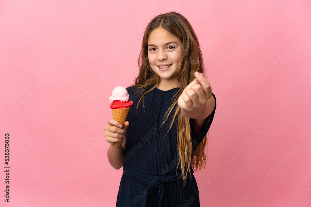 Child with a cornet ice cream over isolated pink background making money gesture Child with a cornet ice cream over isolated pink background making money gesture