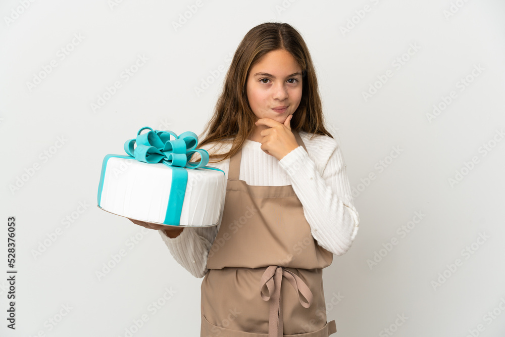 Little girl holding a big cake over isolated white background thinking Little girl holding a big cake over isolated white background thinking