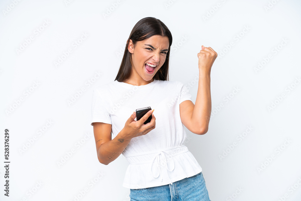 Young caucasian woman isolated on white background with phone in victory position