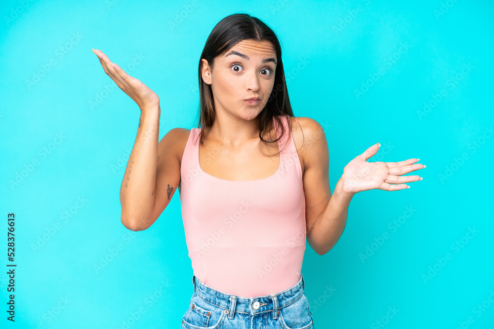 Young caucasian woman isolated on blue background making doubts gesture Young caucasian woman isolated on blue background making doubts gesture