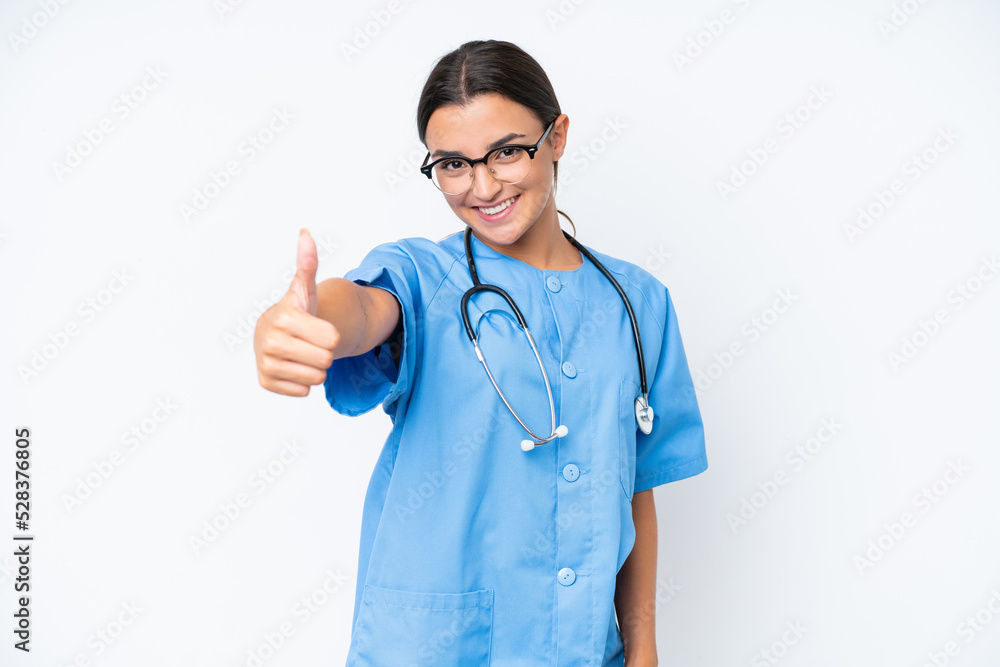 Young nurse woman isolated on white background with thumbs up because something good has happened Young nurse woman isolated on white background with thumbs up because something good has happened