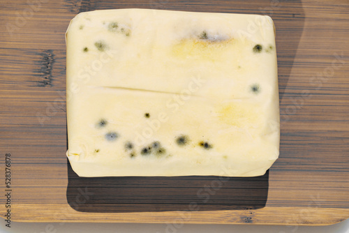 a pack of spoiled butter with mold on a wooden board photo