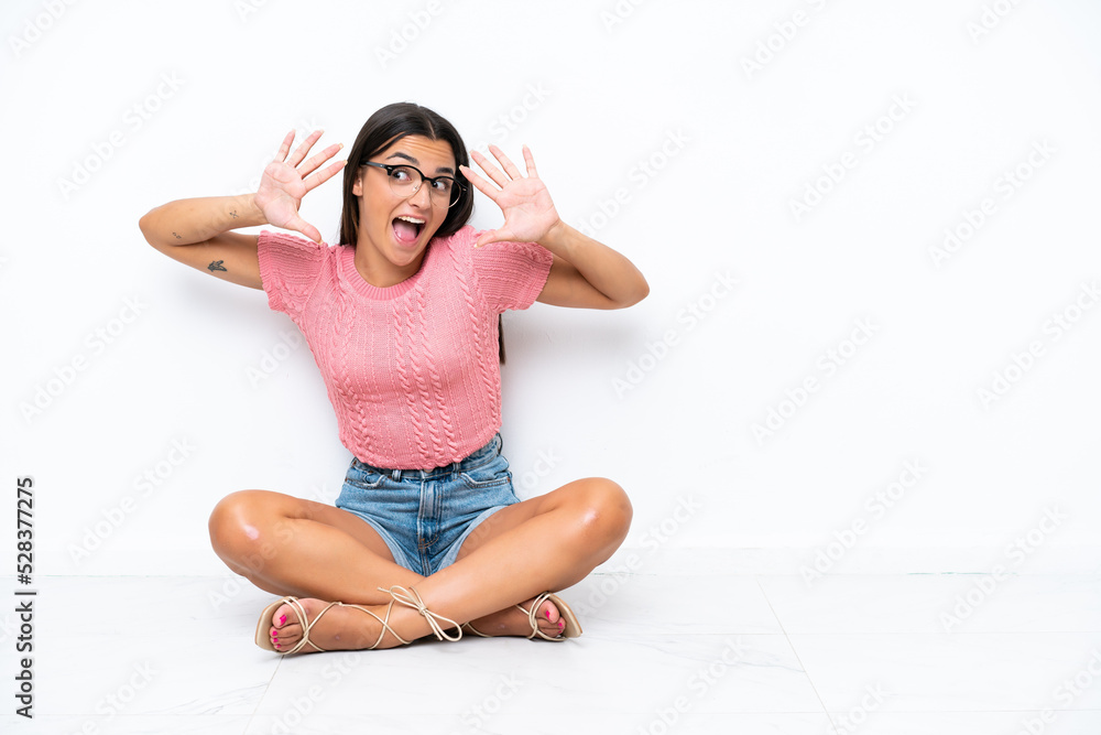 Young caucasian woman sitting on the floor isolated on white background counting ten with fingers