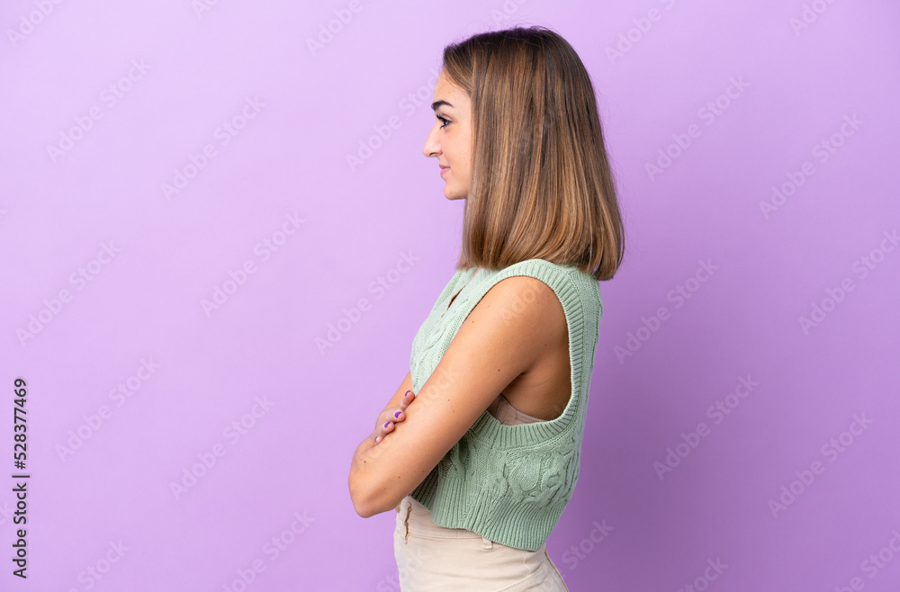 Young caucasian woman isolated on purple background in lateral position Young caucasian woman isolated on purple background in lateral position