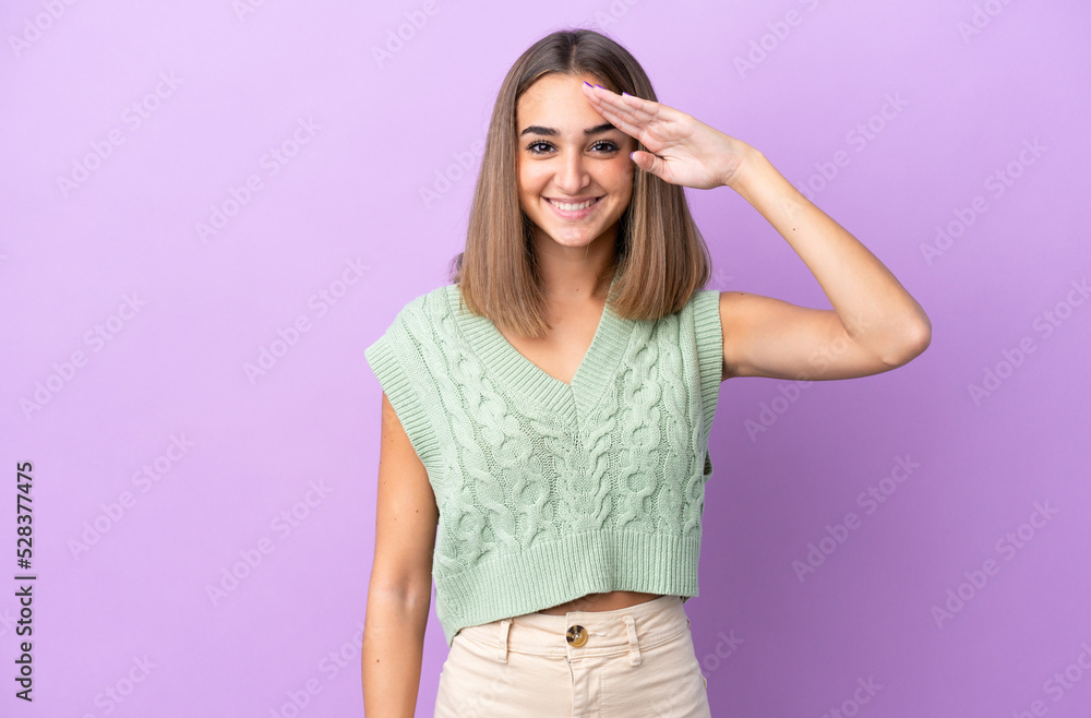 Young caucasian woman isolated on purple background saluting with hand with happy expression Young caucasian woman isolated on purple background saluting with hand with happy expression