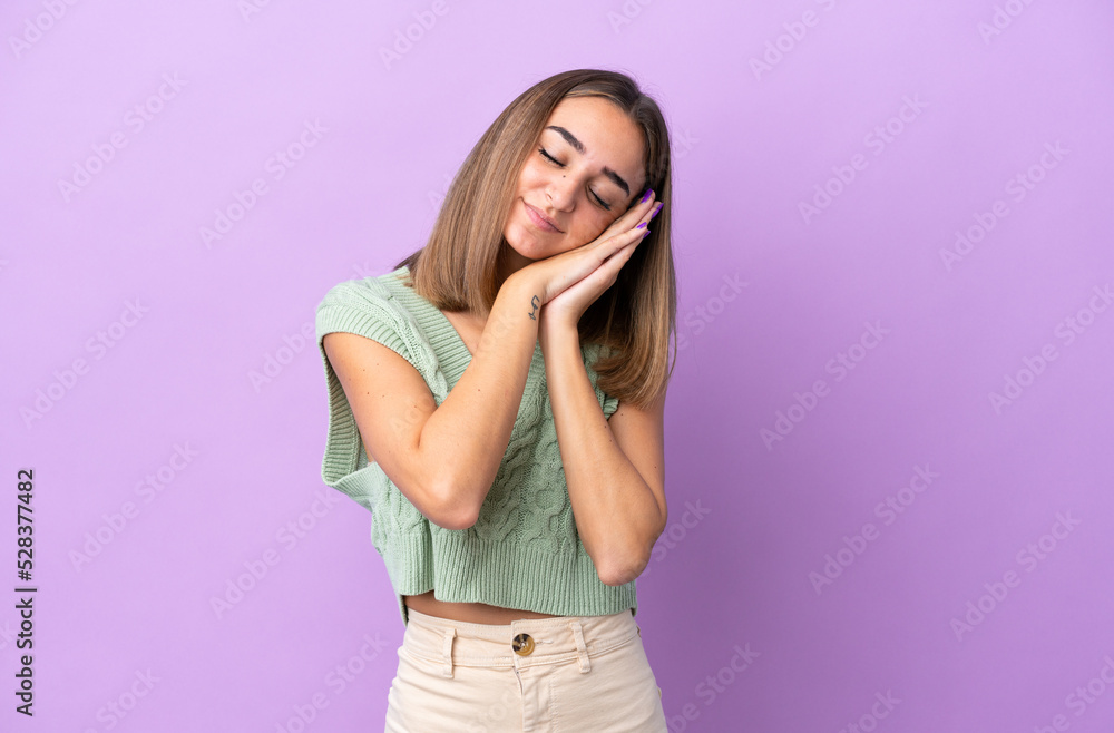 Young caucasian woman isolated on purple background making sleep gesture in dorable expression Young caucasian woman isolated on purple background making sleep gesture in dorable expression