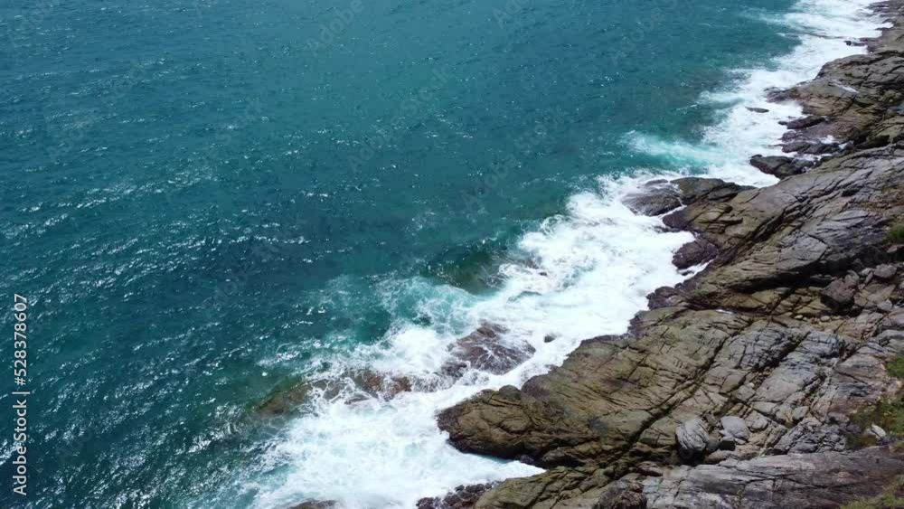 Aerial view of sea waves crashing on rocks cliff in the blue ocean. Top view of coastal rocks in Phuket ocean. Landscape view point of Laem Phromthep Cape in the morning. Aerial view of sea waves crashing on rocks cliff in the blue ocean. Top view of coastal rocks in Phuket ocean. Landscape view point of Laem Phromthep Cape in the morning.