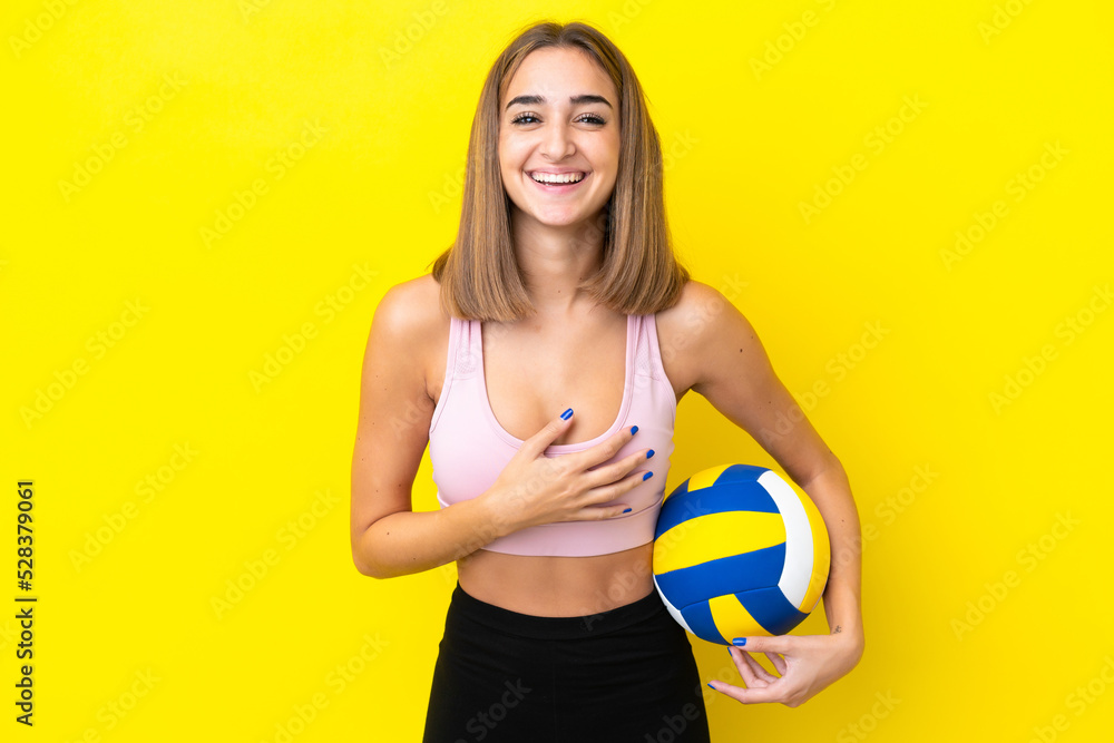 Young woman playing volleyball isolated on yellow background smiling a lot Young woman playing volleyball isolated on yellow background smiling a lot