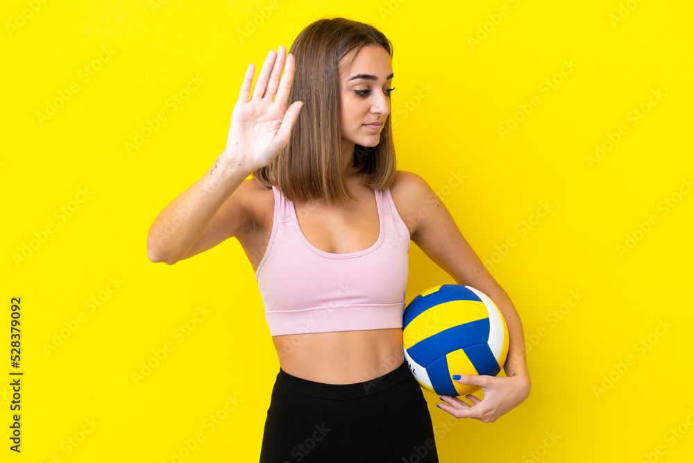 Young woman playing volleyball isolated on yellow background making stop gesture and disappointed Young woman playing volleyball isolated on yellow background making stop gesture and disappointed
