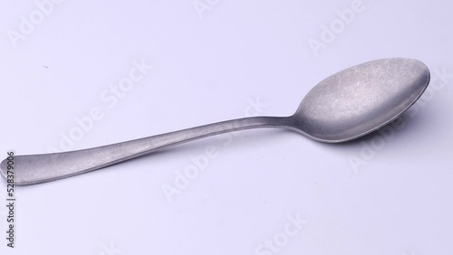 Frosted spoon is spinning on the table, video of cutlery white background