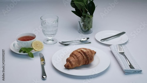 One Croissant with tea. Close-up 4k video footage, white background