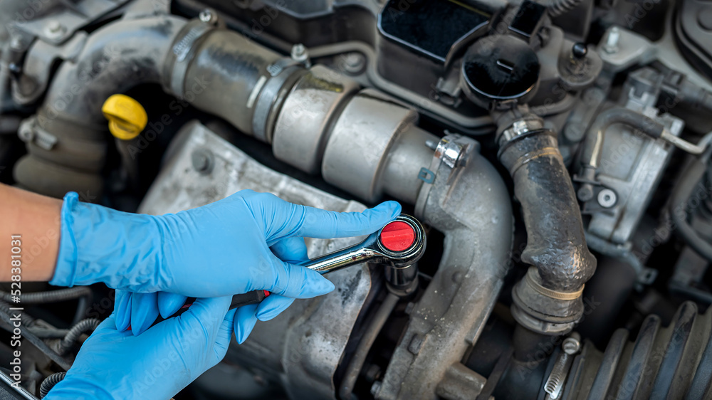 hands of a female mechanic working under the hood of a car in a car service. hands of a female mechanic working under the hood of a car in a car service.