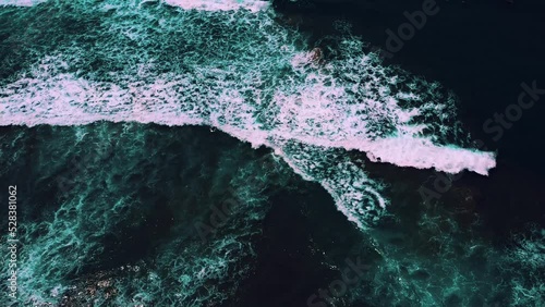 Aerial view of people surfing on sea waves against a sandy beach