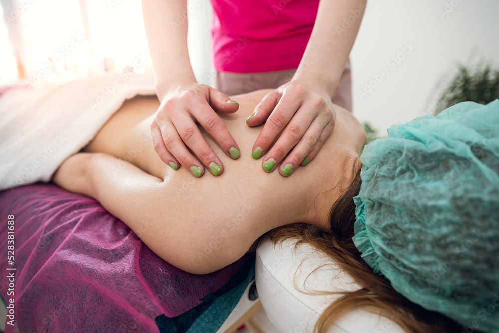 female therapist specialist makes anti-cellulite massage on back woman client at spa salon