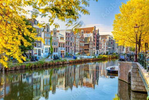 Autumn morning in Amsterdam. Silence. Ancient houses are reflected in the water of the canal, the sun shines through the trees. Lovely morning in Amsterdam.