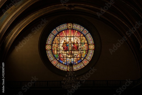 Interior view of an old church with a stained glass window of religious paintings