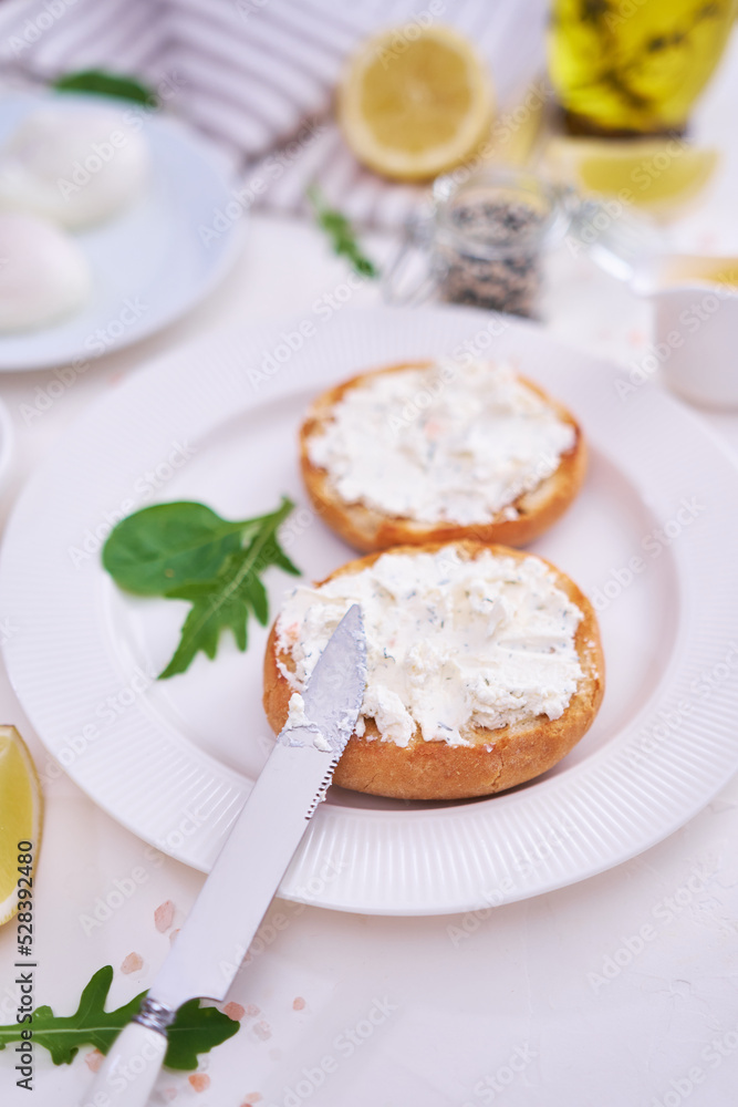 Grilled buns with cream cheese smeared with poached eggs on background