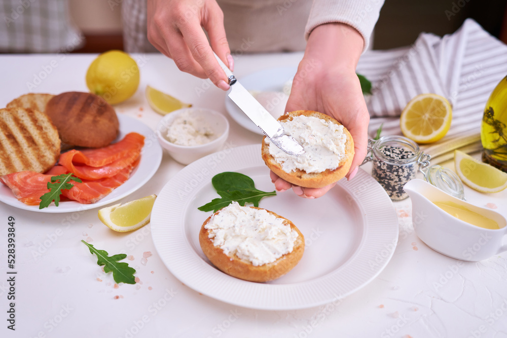 Making cream cheese and salmon toatst - woman smearing cream cheese on a grilled bun Making cream cheese and salmon toatst - woman smearing cream cheese on a grilled bun