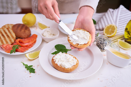 Making cream cheese and salmon toatst - woman smearing cream cheese on a grilled bun