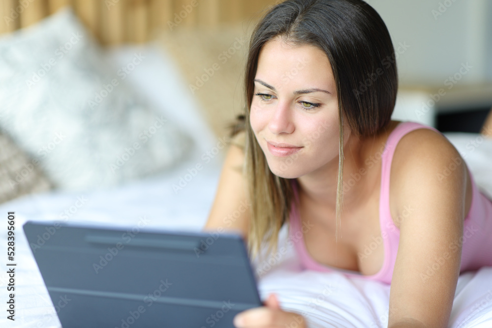 Happy woman using tablet on a bed at home Happy woman using tablet on a bed at home