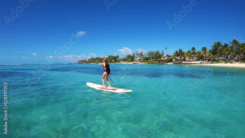 Woman paddling on a stand up paddle board in front of the coast of Mauritius