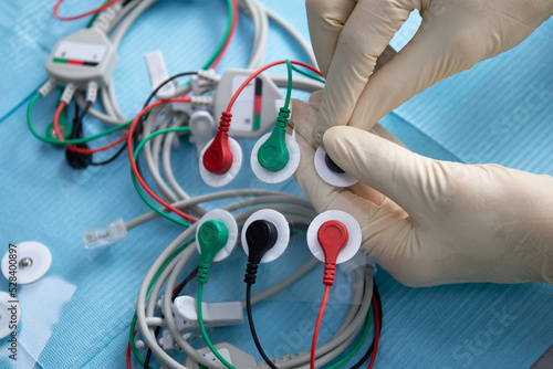 Hands in a gloves connect electrodes for nerve stimulation device in stomatology photo