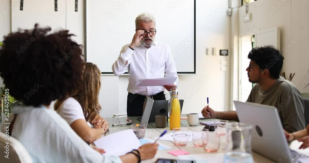 Senior businessman speaking in front of colleagues at meeting Senior businessman speaking in front of colleagues at meeting
