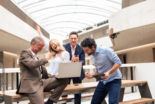 Cheerful business colleagues celebrating success in corridor photo