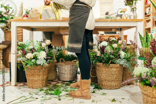 Woman standing by flowers in basket at floral shop photo
