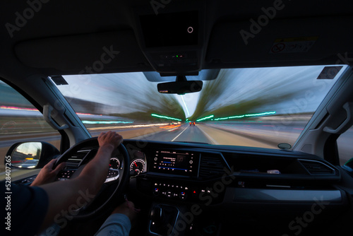 Interior view of a person driving a car with long exposure light trails.