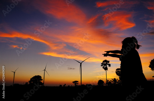 Silhouette of two girls pointing at wind turbines at sunset, Jeneponto, South Sulawesi, Indonesia photo