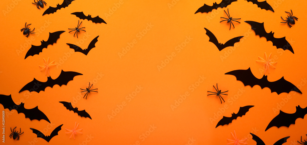 Orange Halloween background. Flock of black bats for Halloween. Black paper bat silhouettes on orange background. Halloween concept, Copy space, top view, overhead. Banner. Orange Halloween background. Flock of black bats for Halloween. Black paper bat silhouettes on orange background. Halloween concept, Copy space, top view, overhead. Banner.
